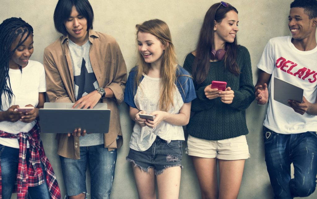 teens smiling and looking on their gadgets