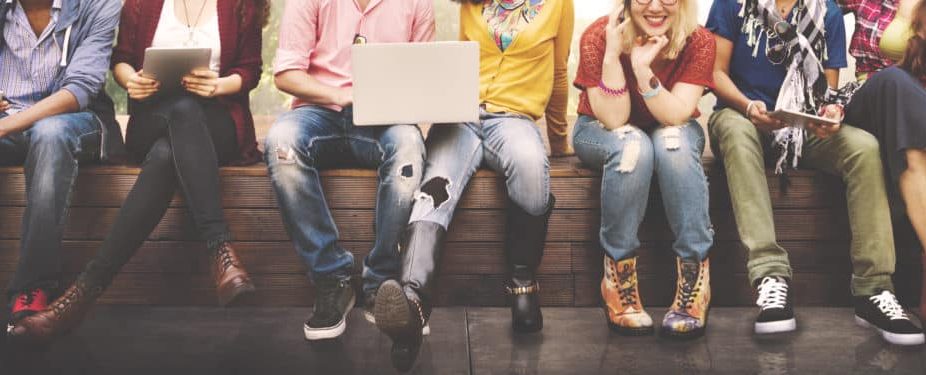 teens sitting down, having a chit chat while holding a laptop