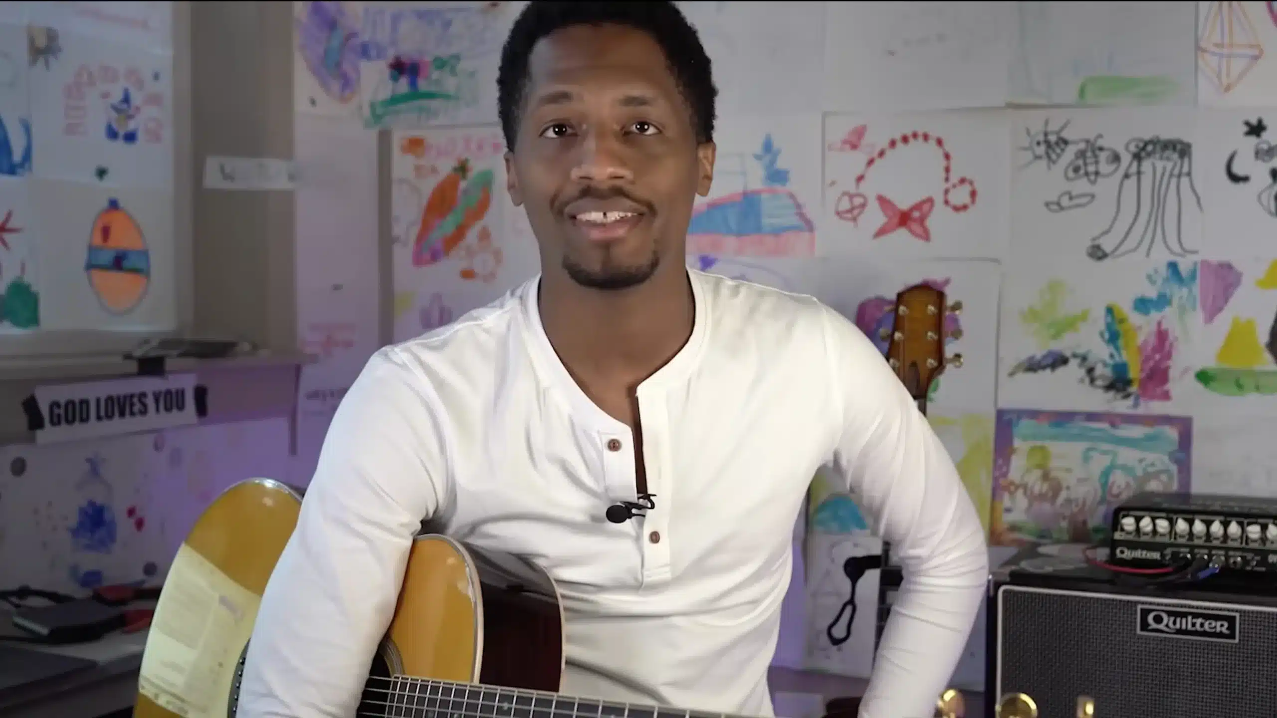 ron artis with his guitar and kids painting at the background