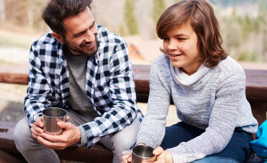 Happy dad and son drinking tea in the forest