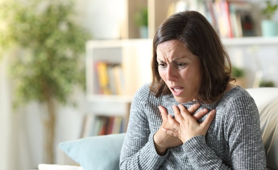 Middle age woman wheezing touching chest at home