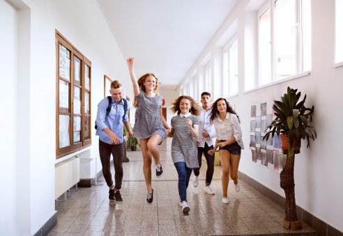Teenage students in high school hall jumping high.