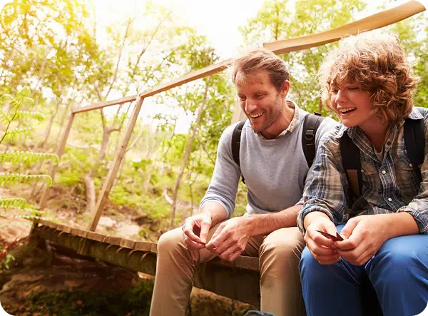 Two person sitting, smiling at something.
